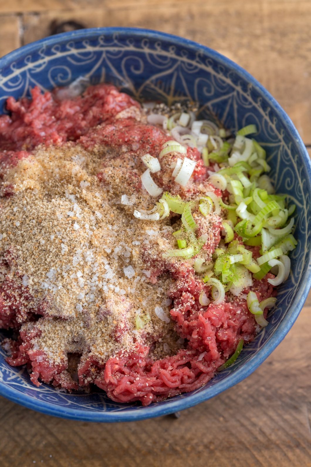Blue bowl with gorund beef, minced spring onion, breadcrumbs and egg white.