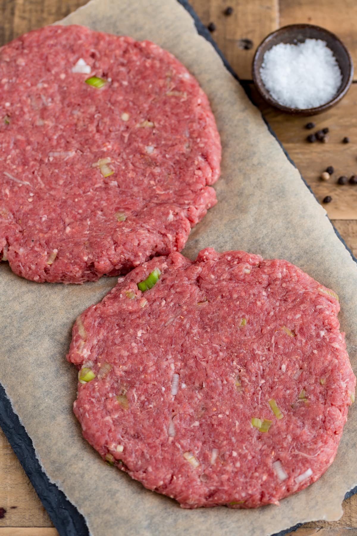 Two homemade beef patties, uncooked.