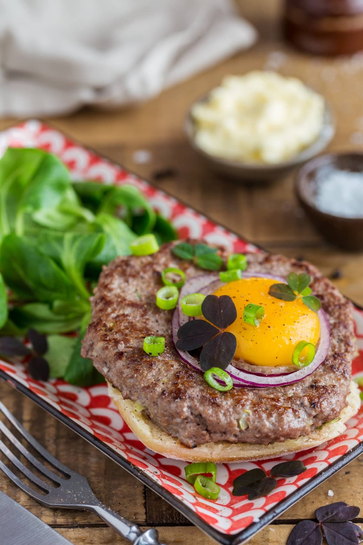 Open sandwich with beef patty and raw egg yolk.