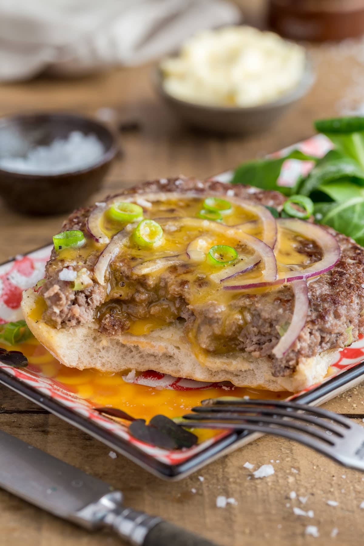Detail of open beef patty sandwich with raw egg yolk pouring over the sides.