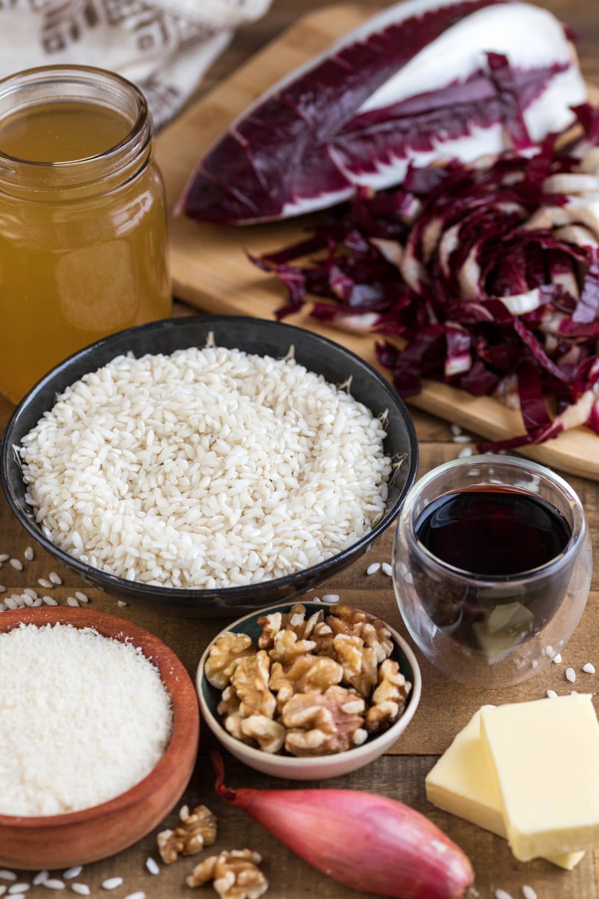Ingredients needed to make radicchio risotto placed on a wooden table.