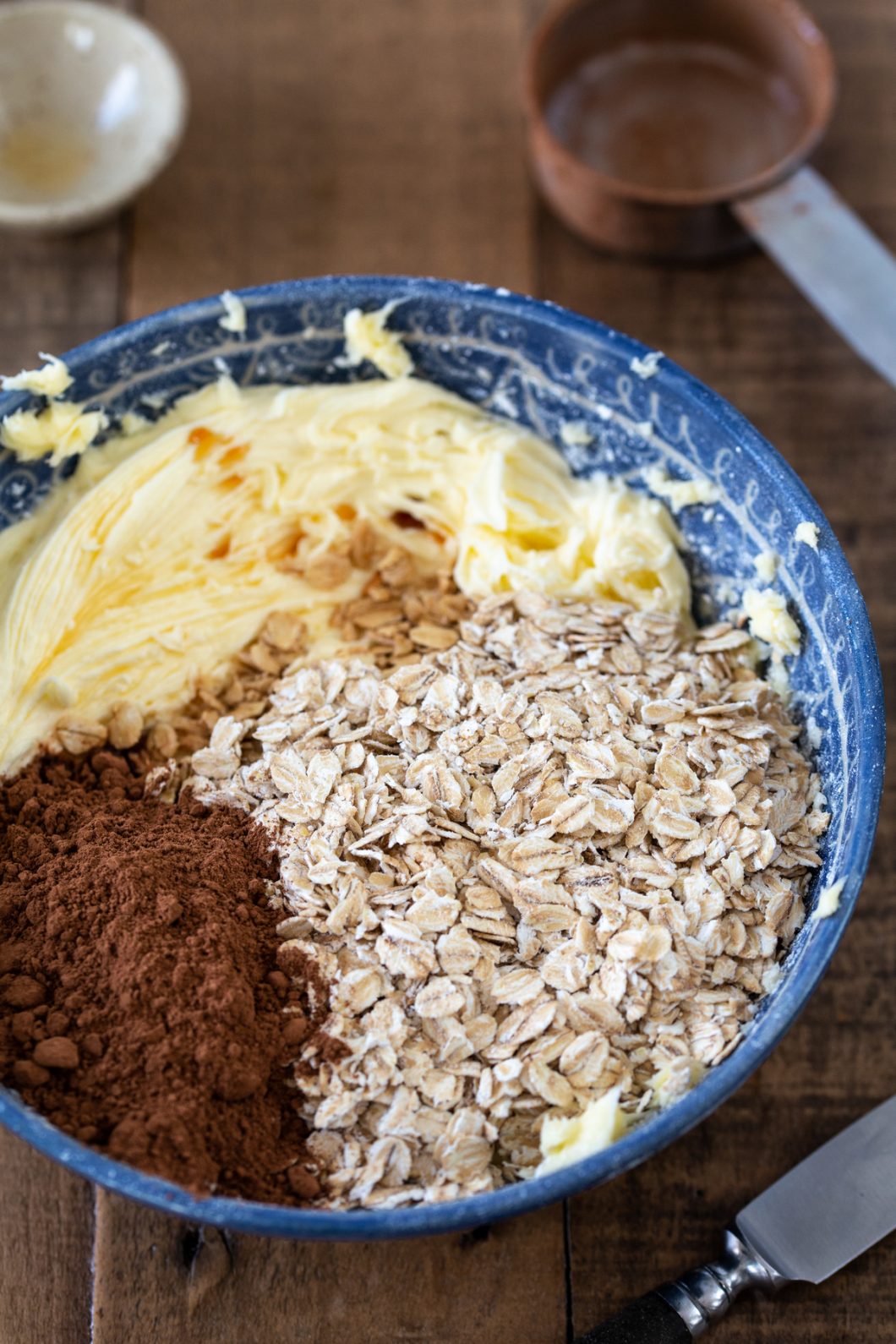 Whipped butter and sugar inb a blue bowl together with rolled oats, cocoa and coffee.