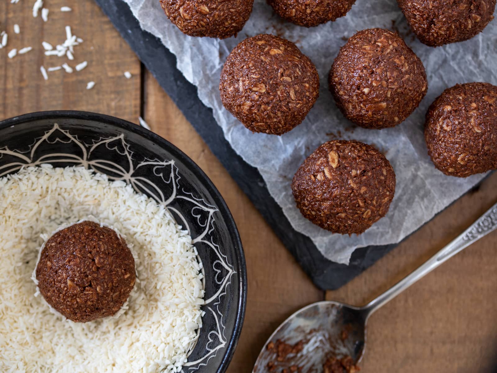 Chocolate oatmeal balls being tossed in shredded coconut.