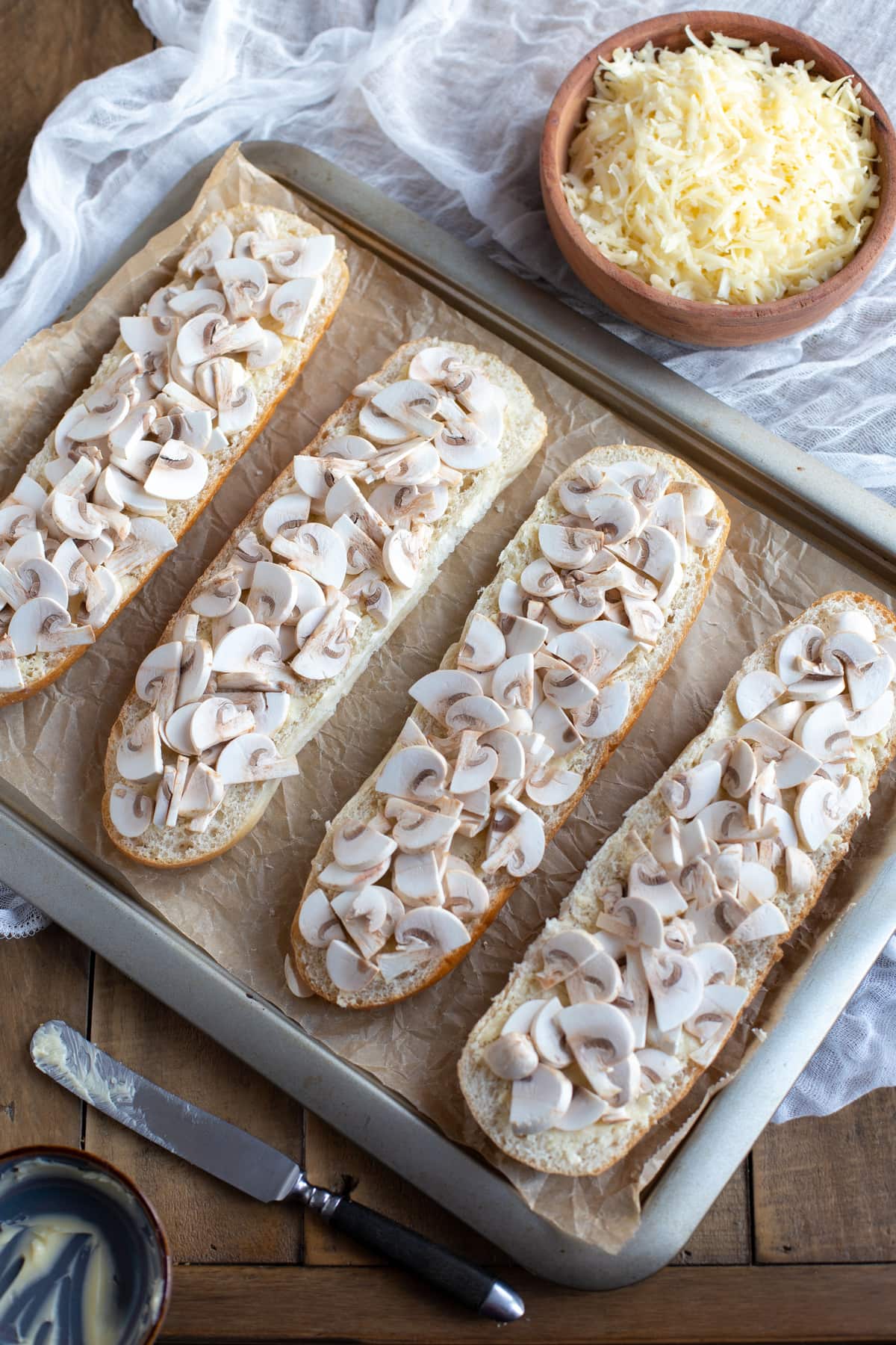 Sliced demi baguettes buttered and topped woth sliced mushrooms.