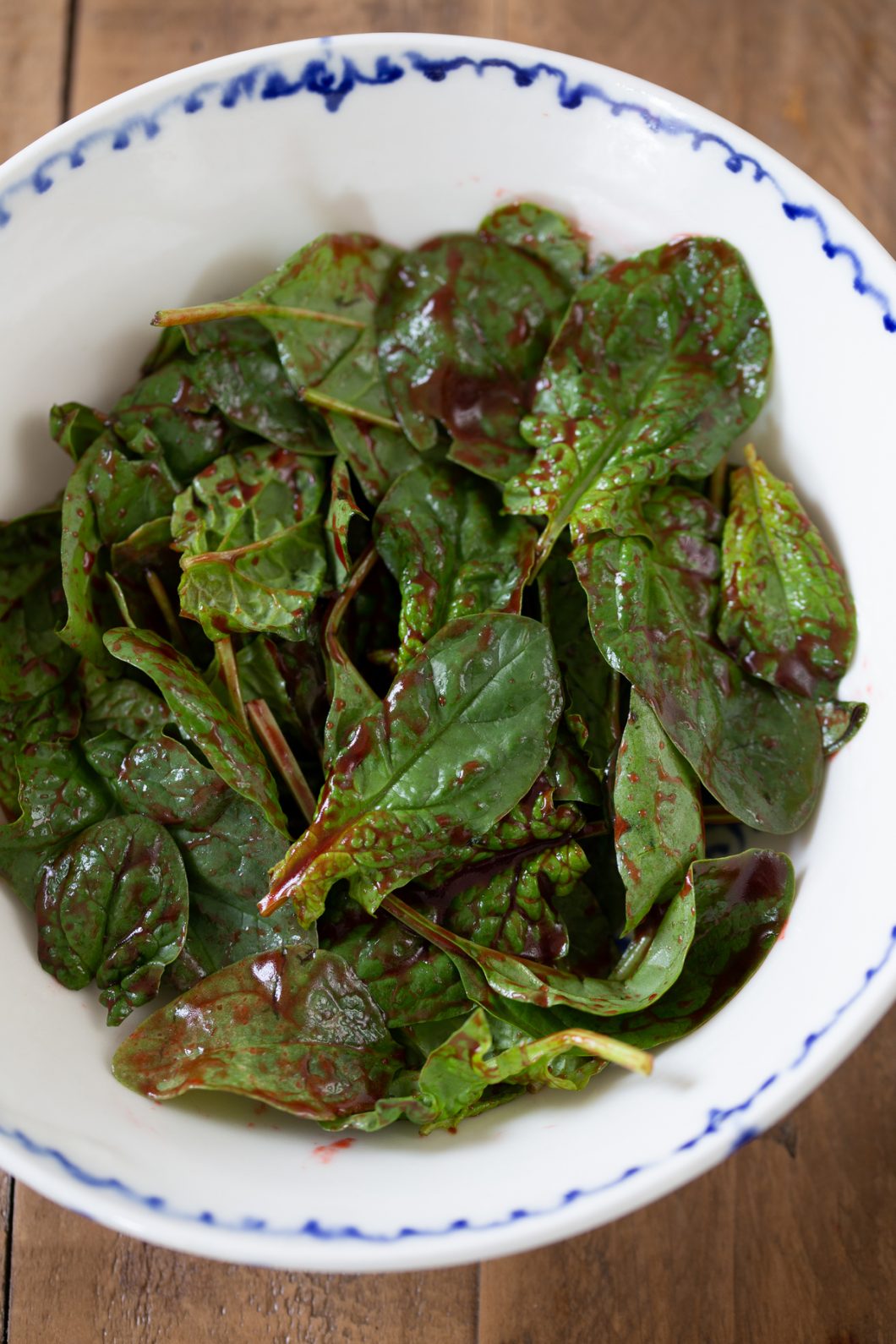 Tossing spinach leaves in dressing.