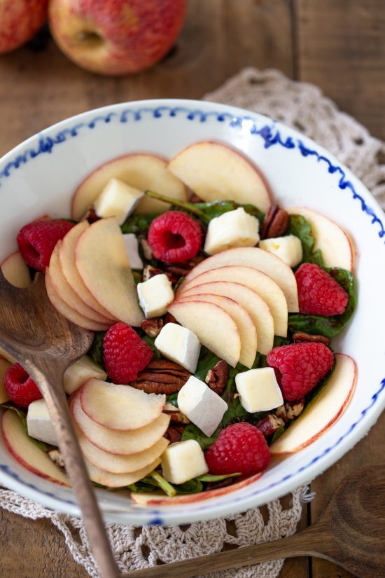 Apple brie and raspberry salad in a white bowl.