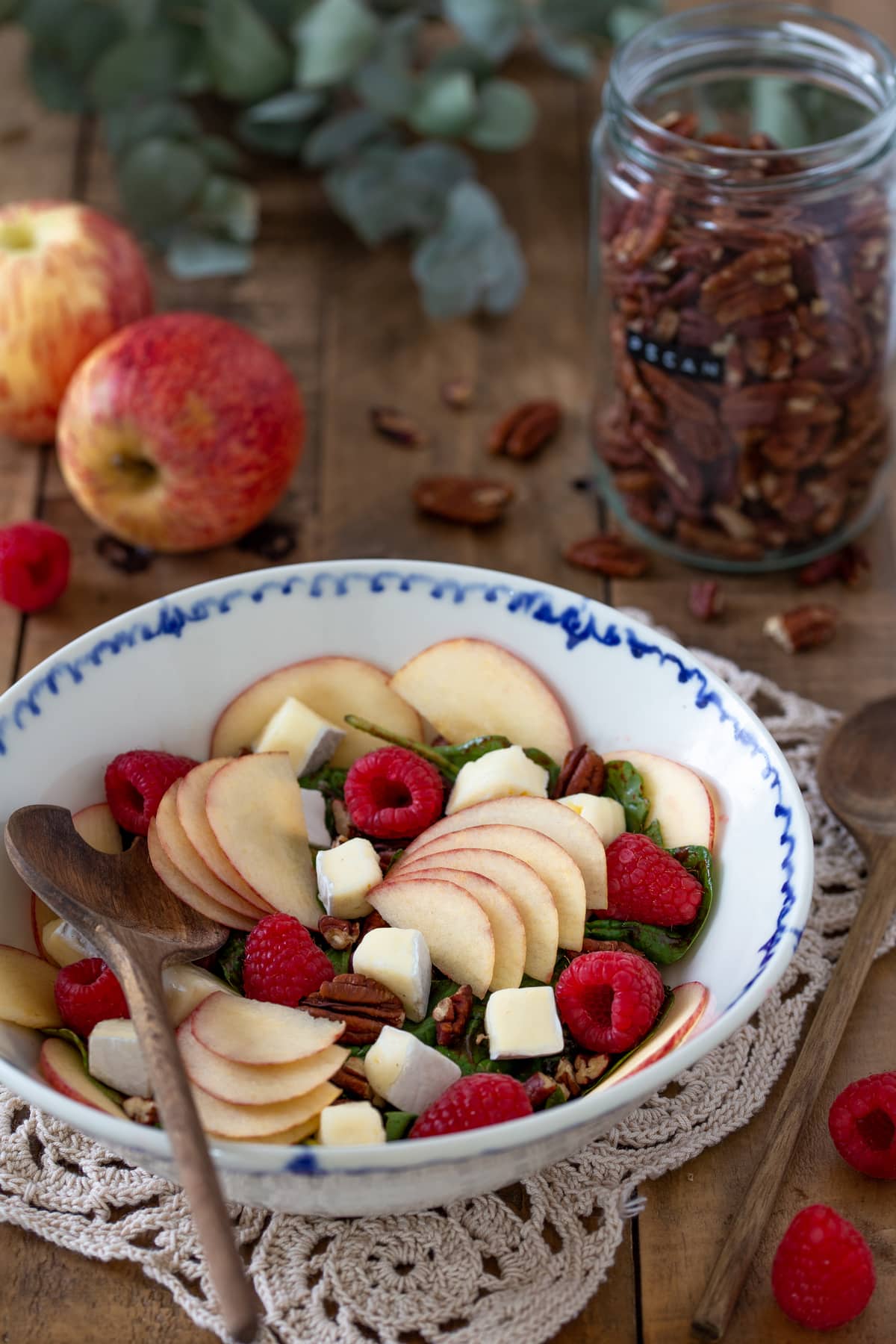 The salad served in a bowl next to other objects.