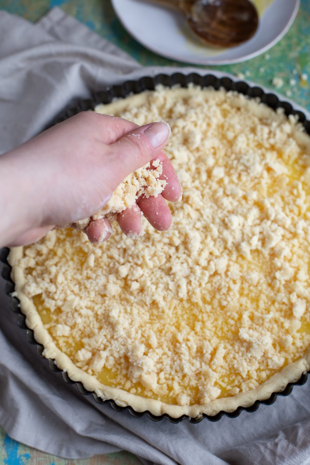 Hand sprinkling pastry crumbles to make streusel topping.