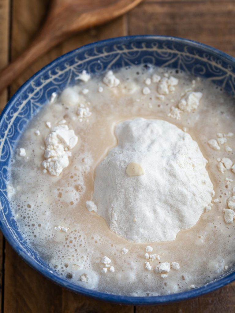 Adding yeast and water mixture to flour.