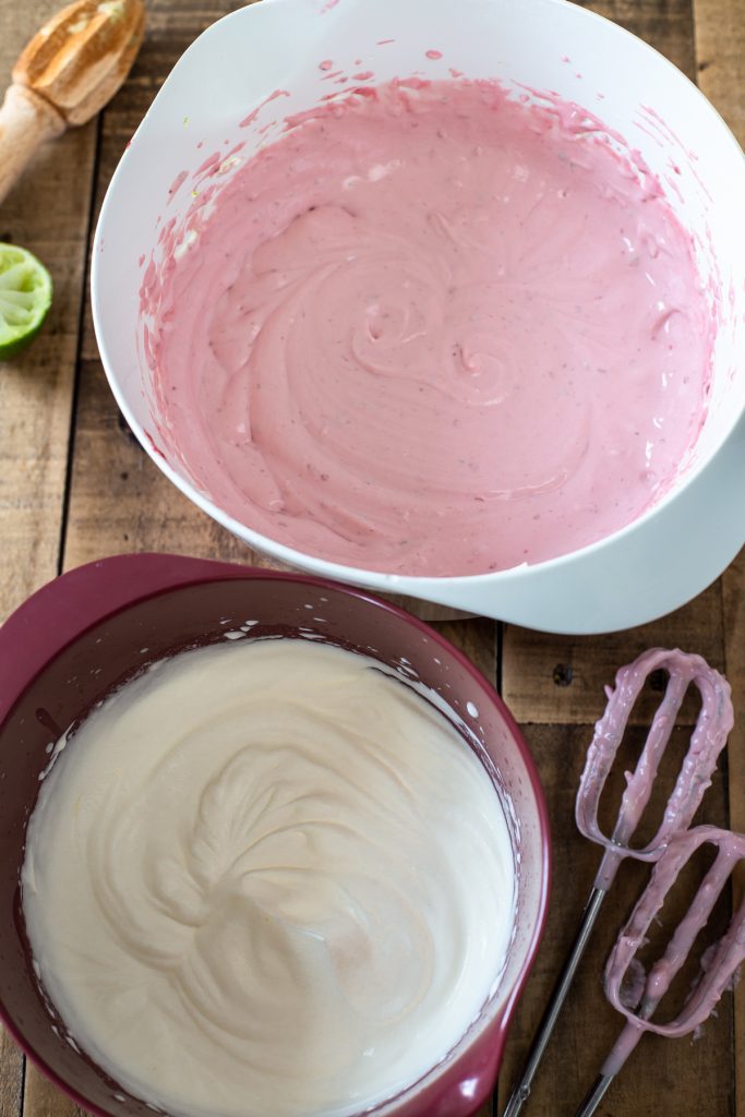 Two bowl with whipped cream and cream cheese raspberry mixture, before combining.