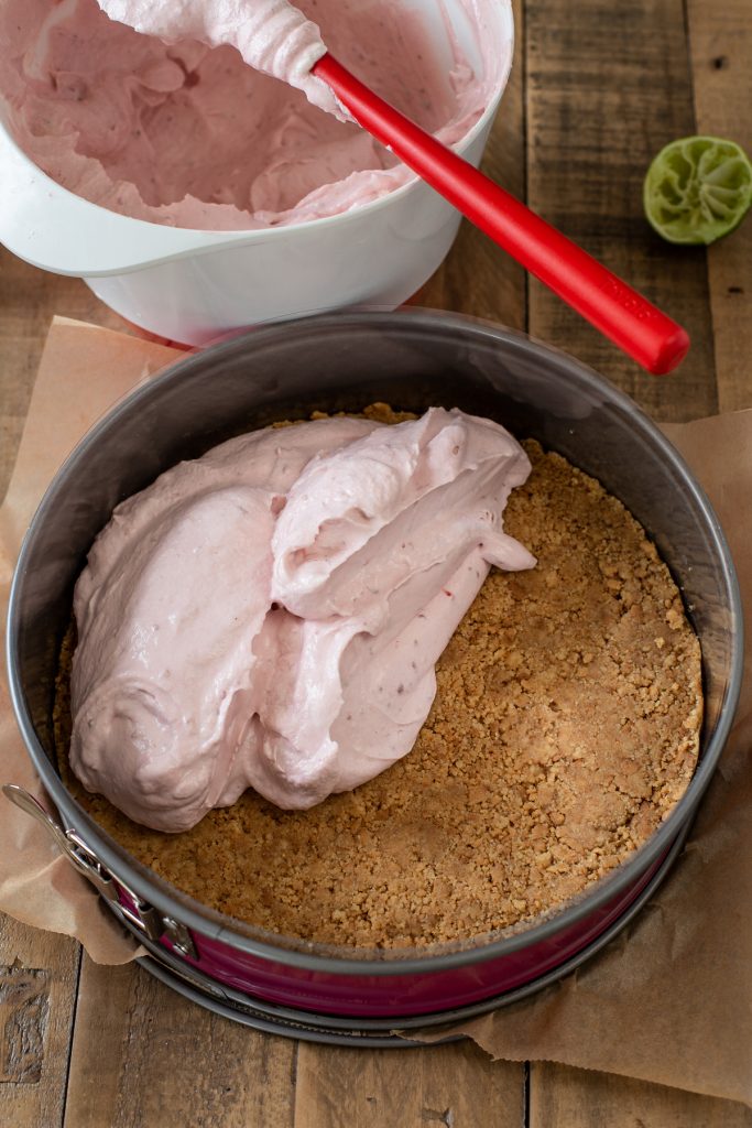 Pouring cheesecake filling over the biscuit base.
