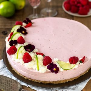 Raspberry chili cheesecake decorated with raspberries, lime, chilies and edible flowers.