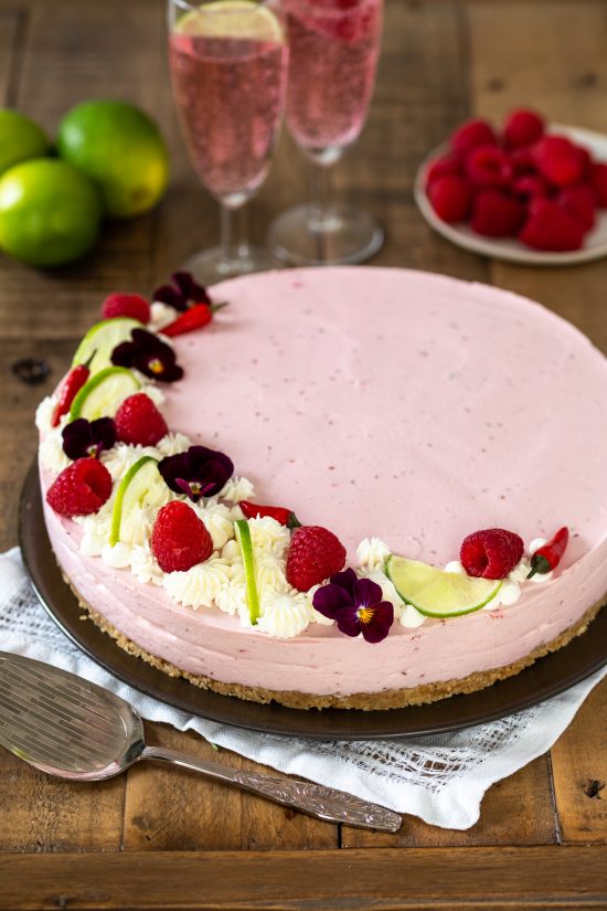 Raspberry chili cheesecake decorated with raspberries, lime, chilies and edible flowers.