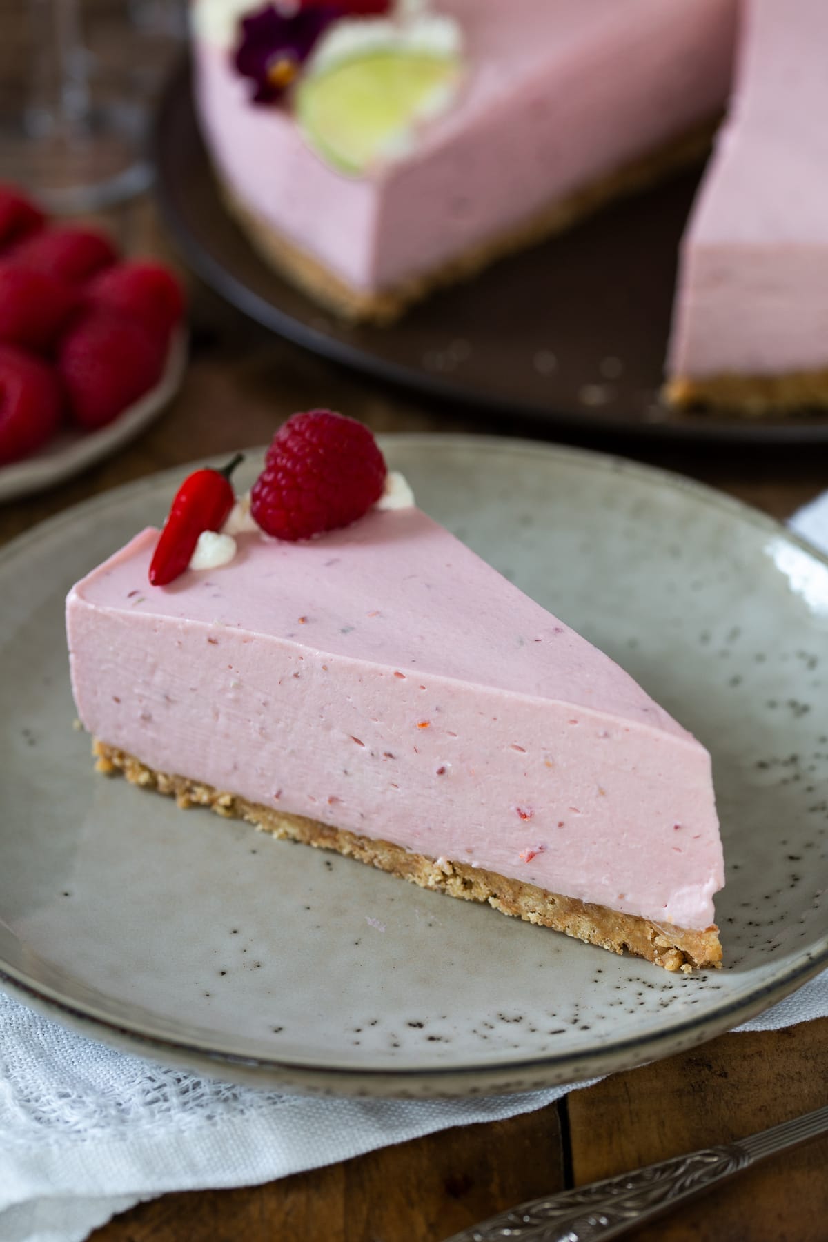 A slice of raspberry cheesecake on a beige plate.