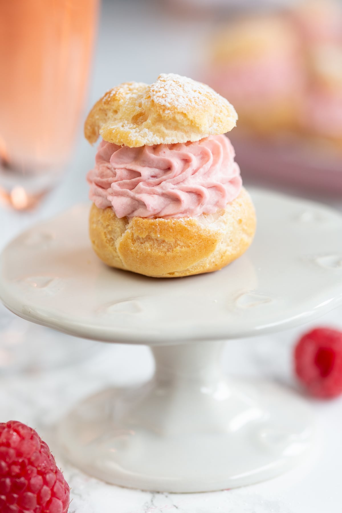 A single cream puff on a small cake stand.