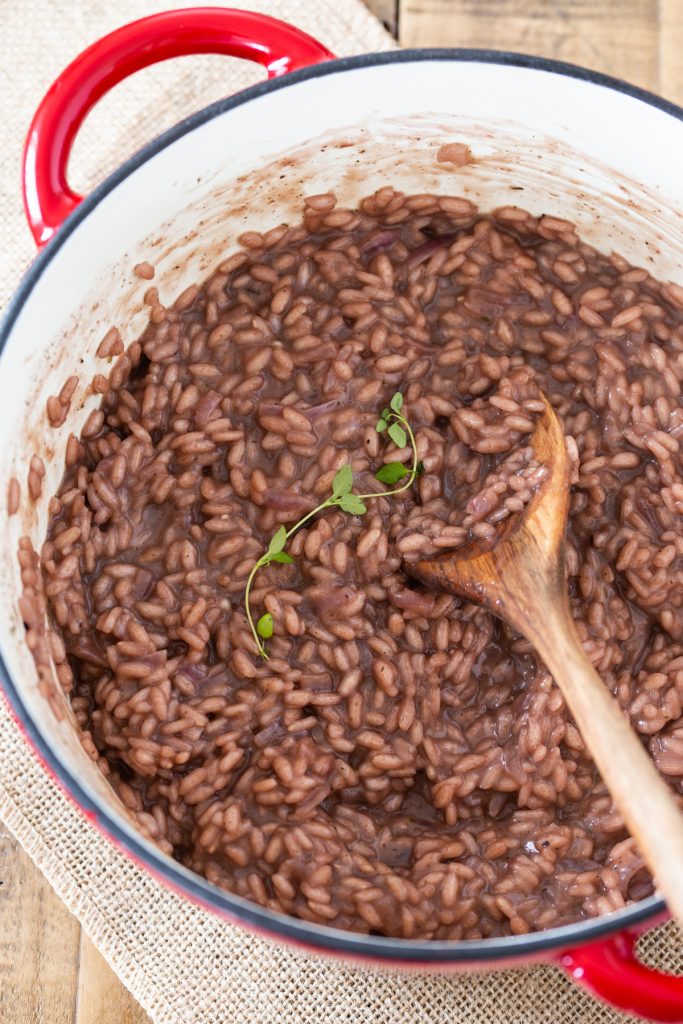 Red wine risotto topped with a sprig of fresh thyme.