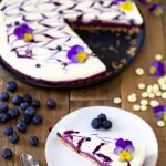 A slice of blueberry no-bake cheesecake with edible flowers.