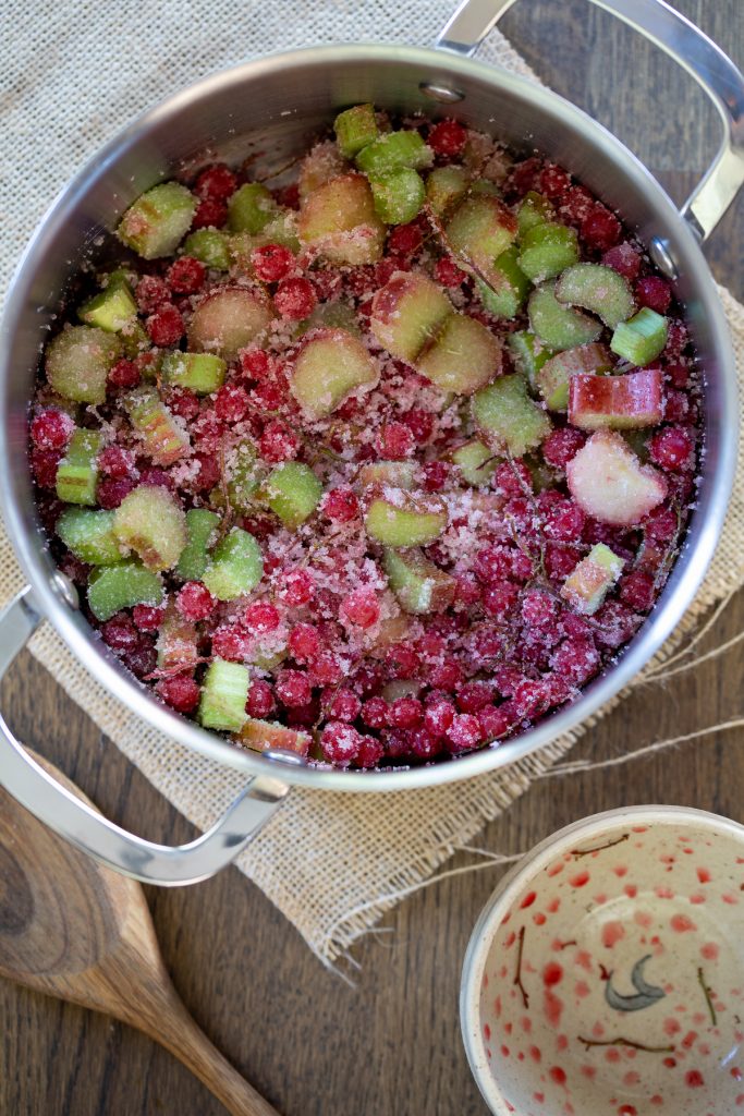 Chopped rhubarb and redcurrants mixed with sugar in a pan.