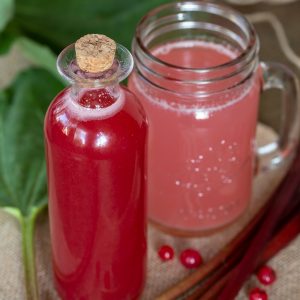 Rhubarb syrup in a bottle, diluted with water in a glass.