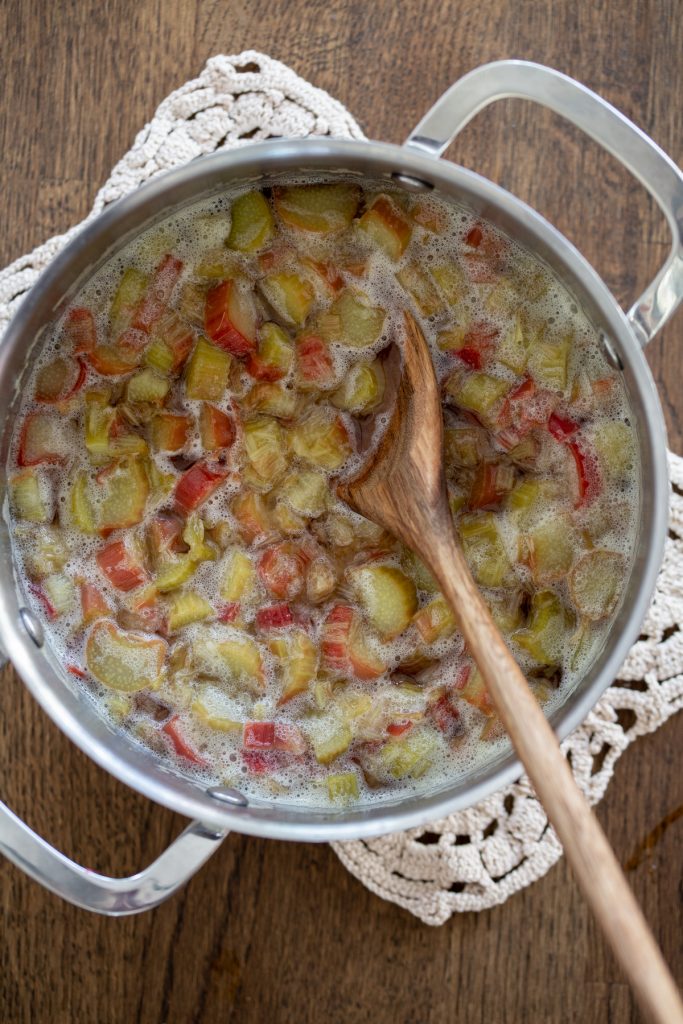 Cooking rhubarb in sugar water until soft.