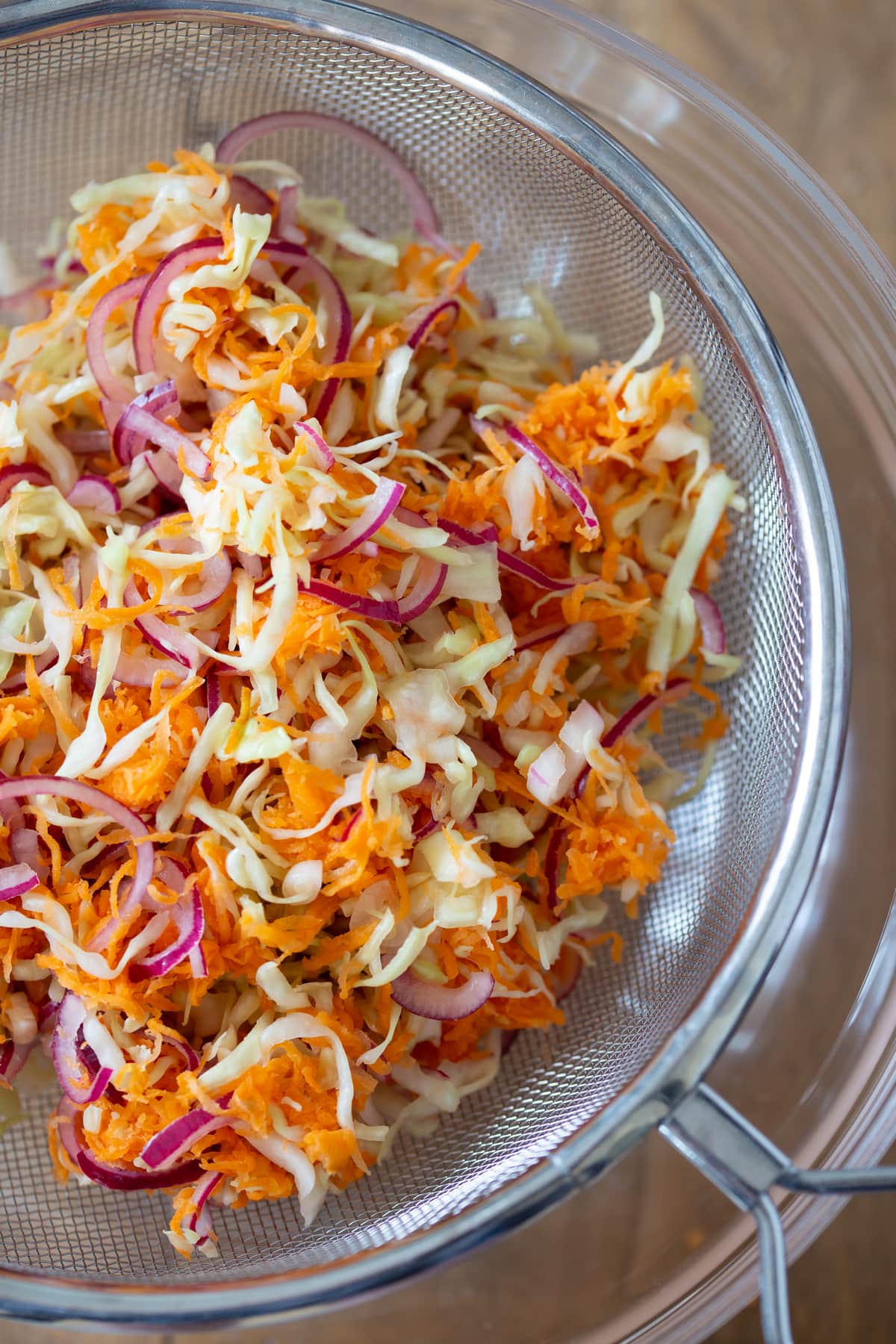 Squeezing out moisture and keeping seasoned veggies on mesh sieve.