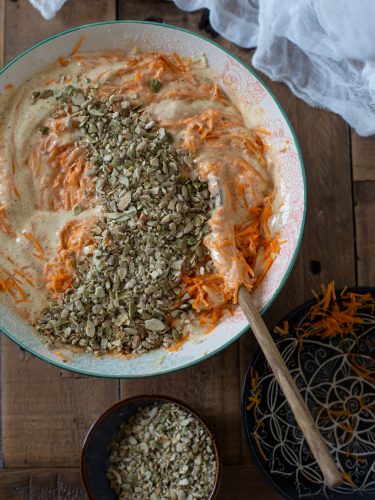 Folding carrots and seeds into cake batter.