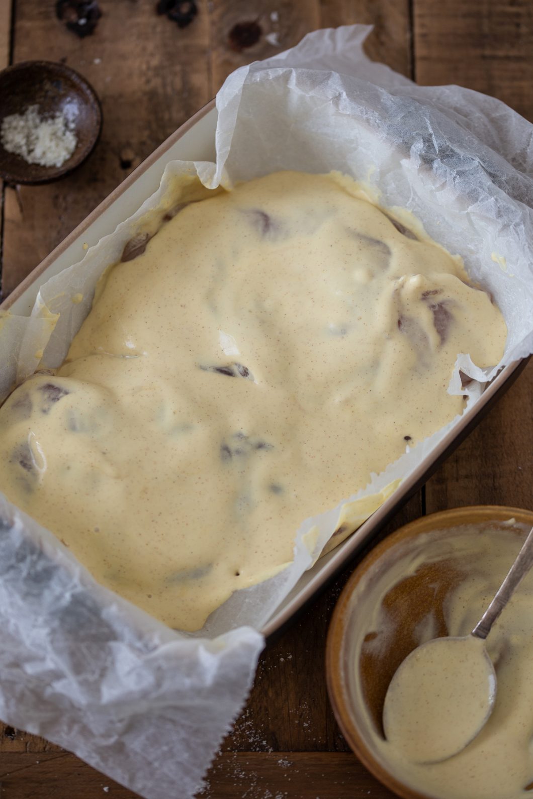 Chicken breasts in a casserole dish, topped with mustard cream condiment.