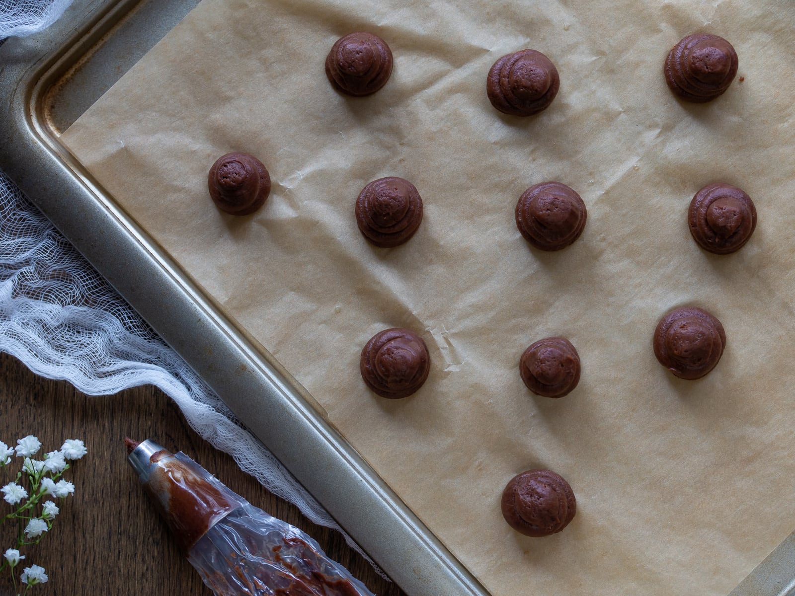 Unbaked cocoa choux pastry lined on a baking tray.