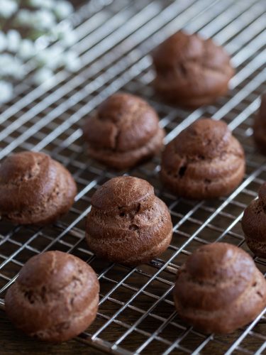 Cocoa choux pastry puffs on a cooling rack.