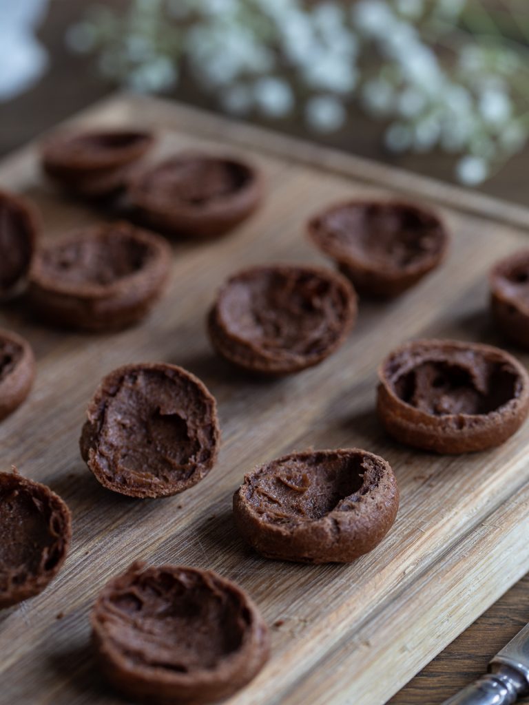 Halved cocoa choux pastry to be filled with cream to make cream puffs.