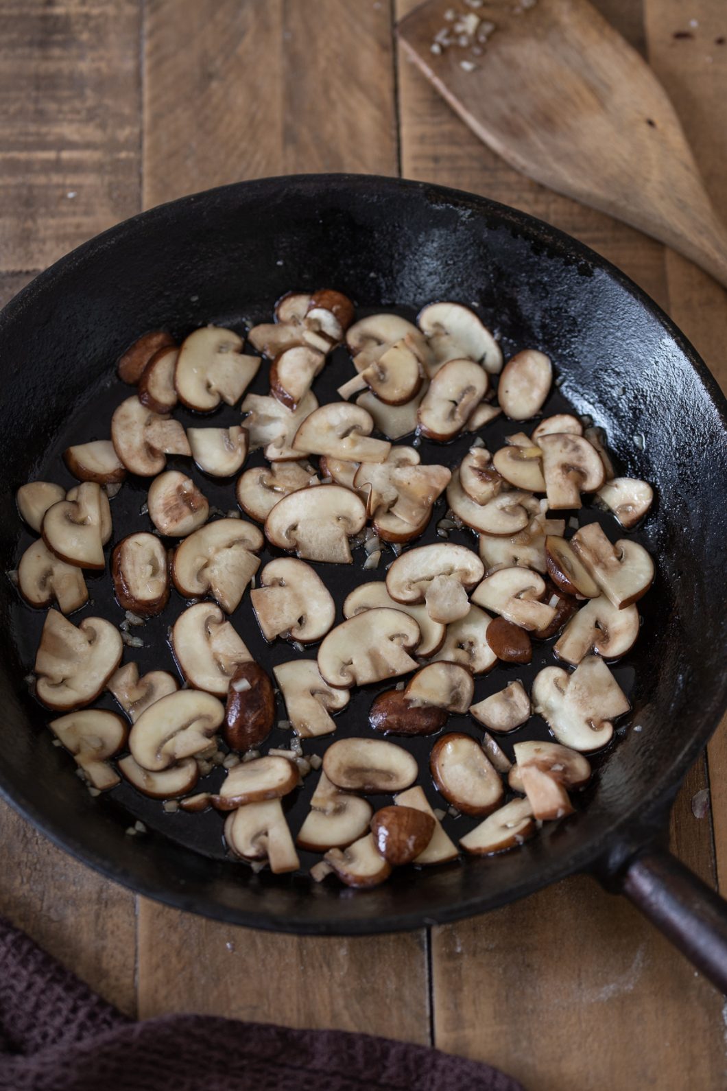 Baby bella mushrooms sautéed in a cast iron pan.