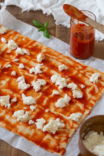 Puff pastry sheet topped with tomato sauce and grated mozzarella.