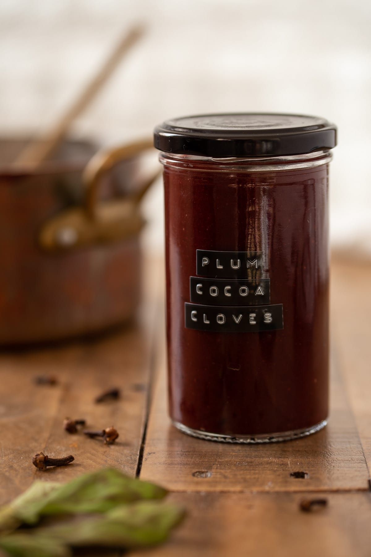 A plum clove cocoa jam in a labelled jar.