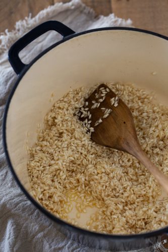 Toasting risotto rice with butter and onion in a cast iron pot.