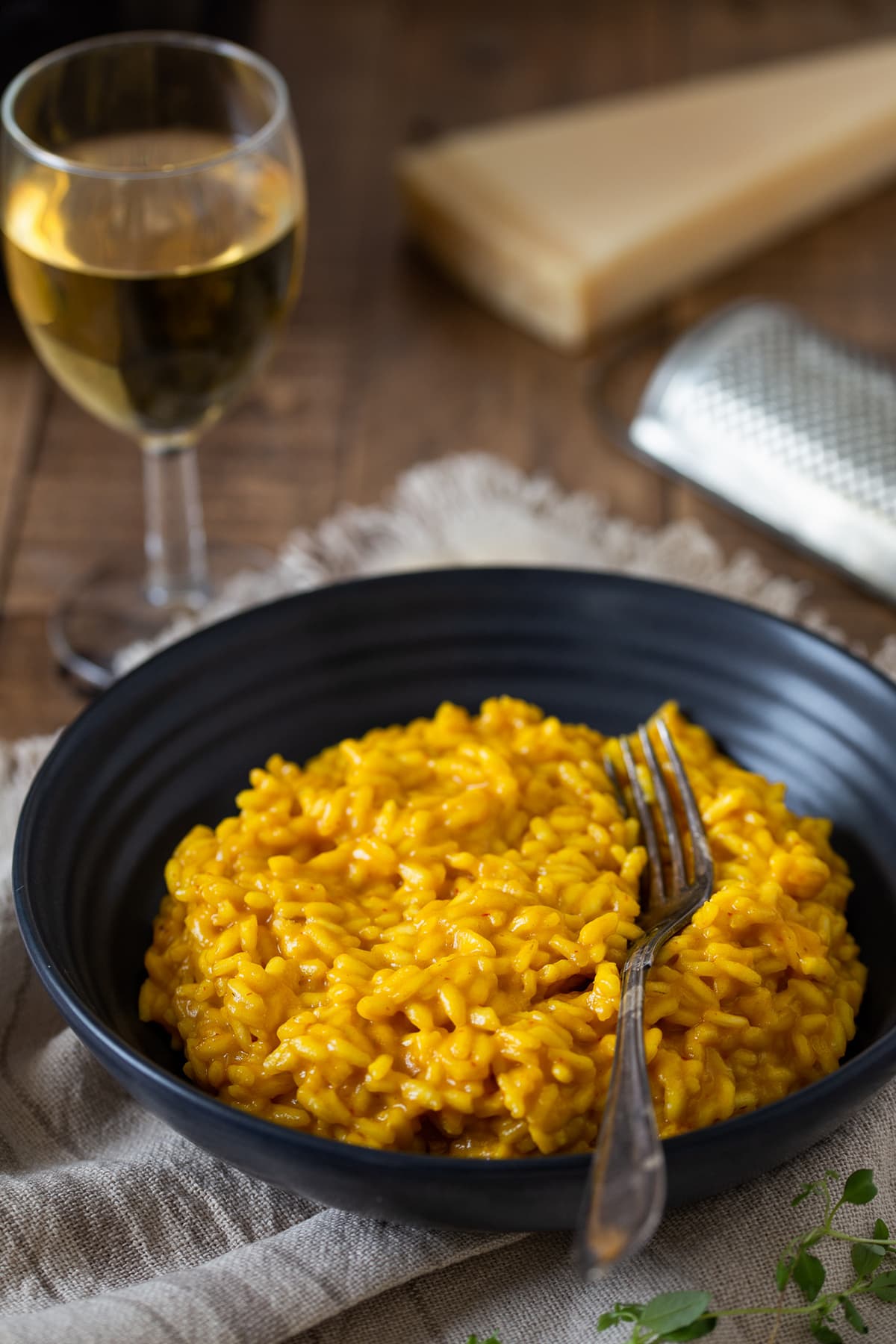 A portion of saffron risotto served with a glass of white wine.