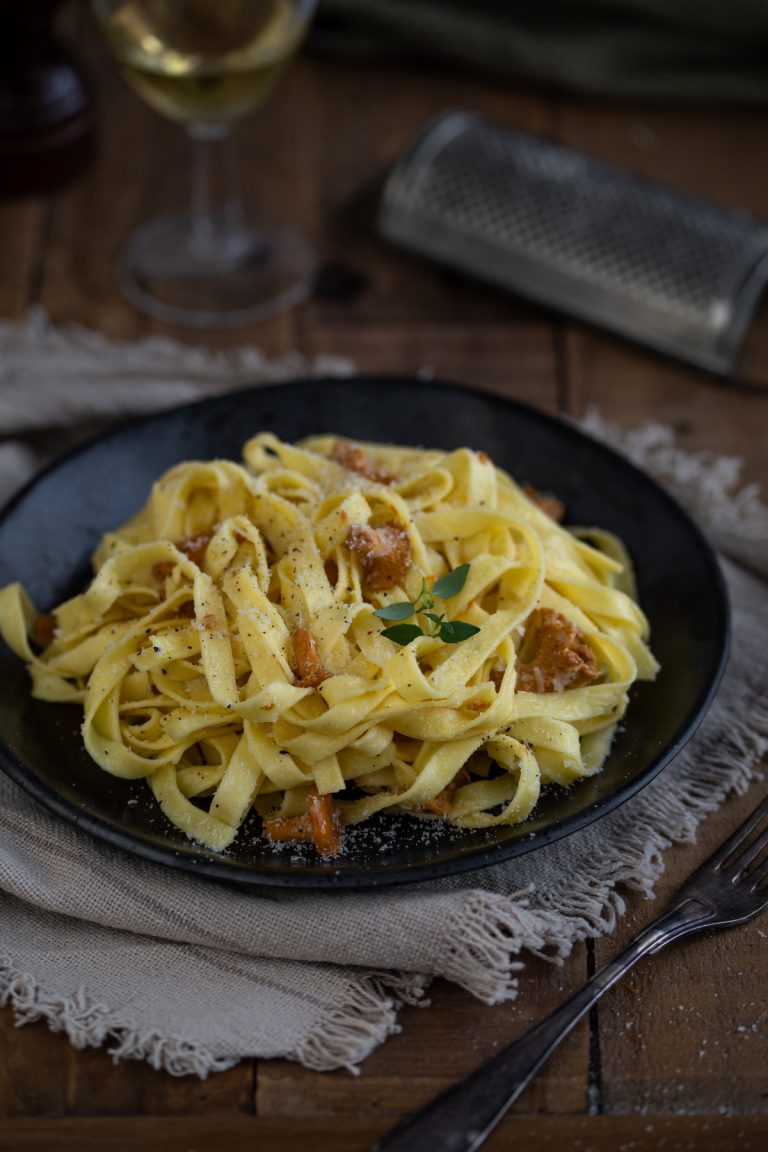Wild mushroom tagliatelle served on a dark plate.