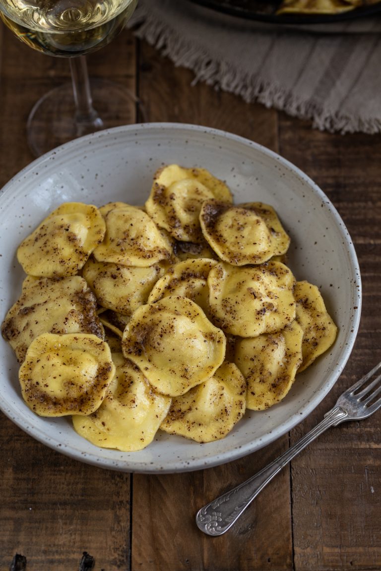 A portion of cheese ravioli with hazelnut butter in a white bowl.