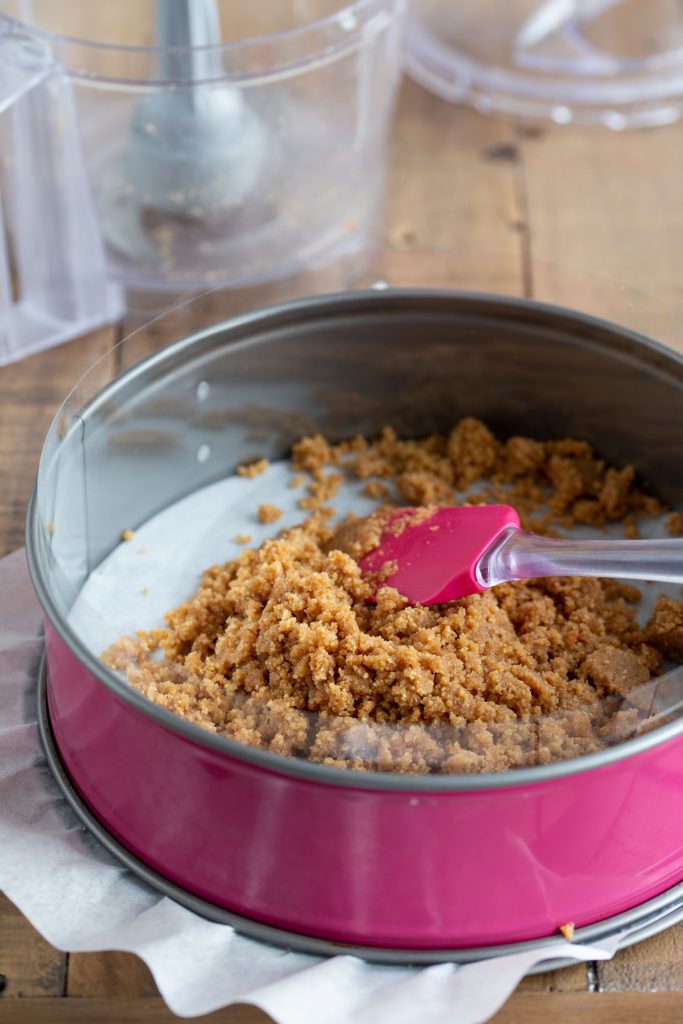 MAking cheesecake base with crumbled digestive biscuits and butter.