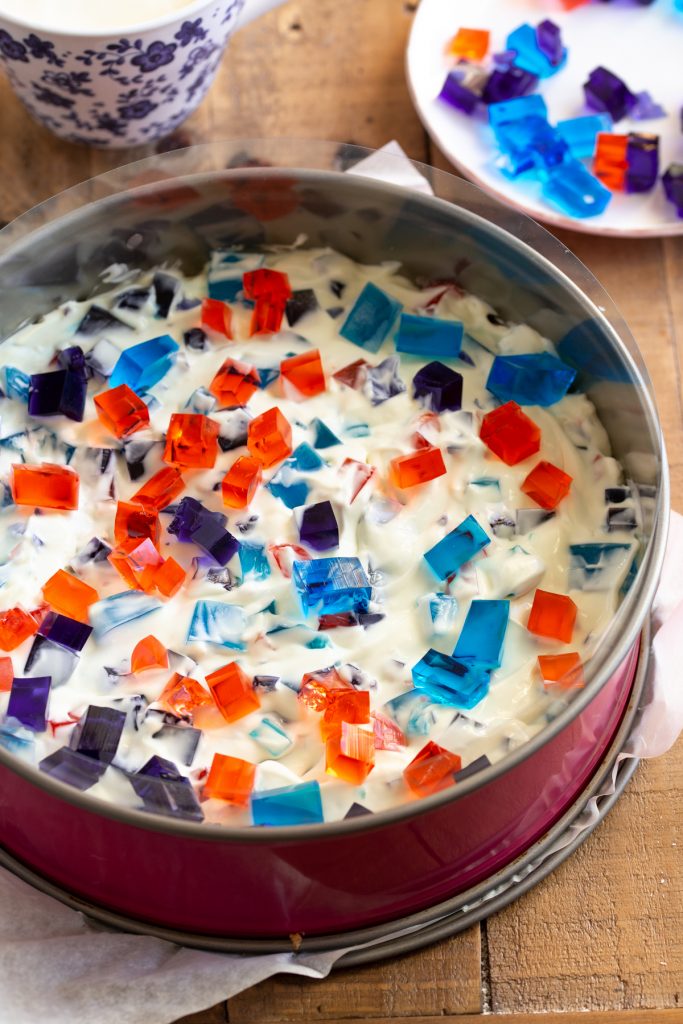 Assembilng the cake by adidng top layer of diced jello.