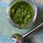 Overhead view of pesto in a jar and immersion blender on the side.