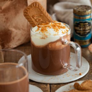 Biscoff hot chocolate topped with whipped cream and a cookie.