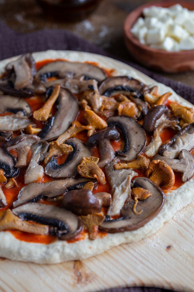 Adding the ingredients to the pizza.