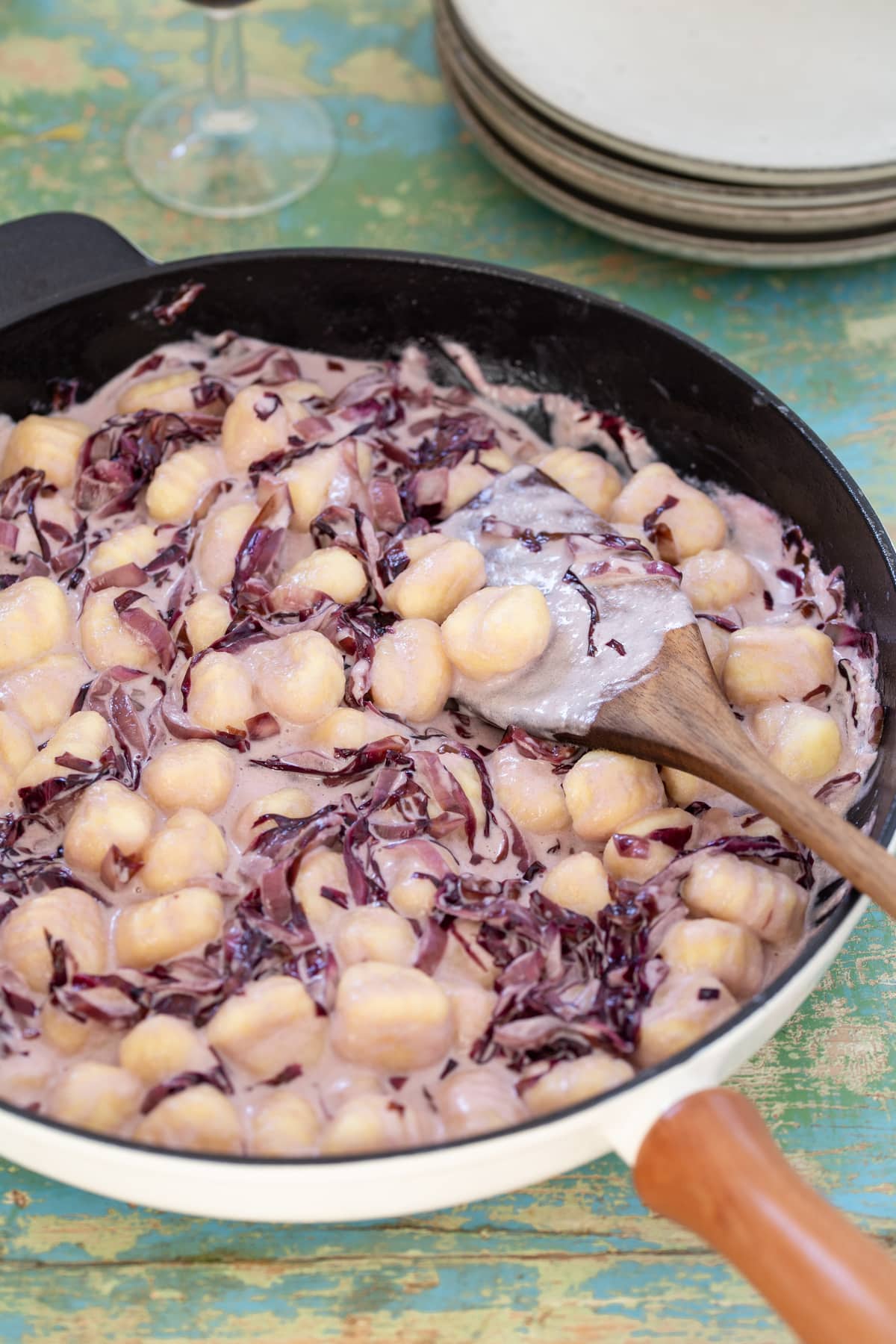 Radicchio gnocchi with cream in a skillet.