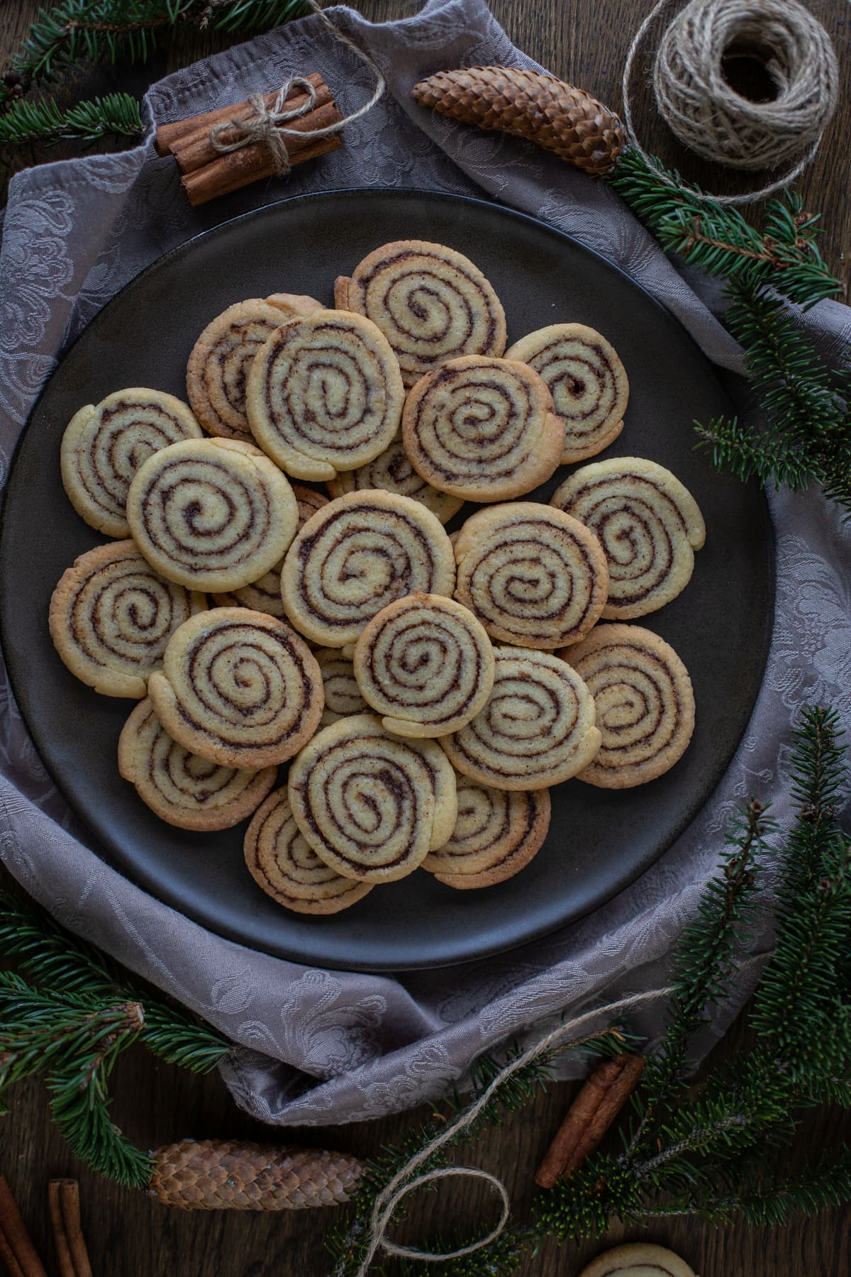 Cinnamon roll cookies on a brown plate with pine decorations.