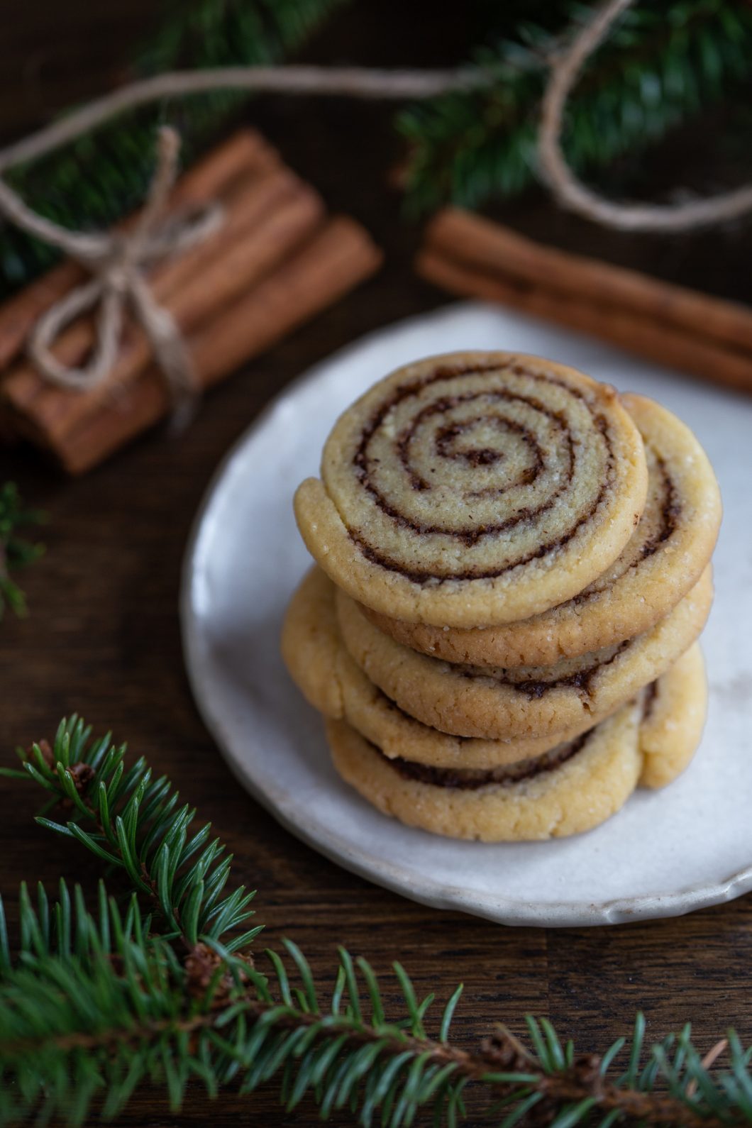 Cinnamon roll cookies stacked on a white plate.