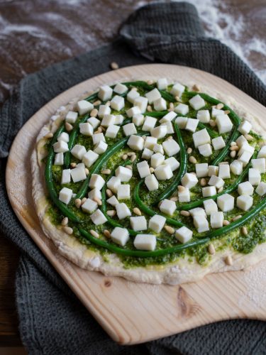 Topping pizza with green beans and mozzarella.