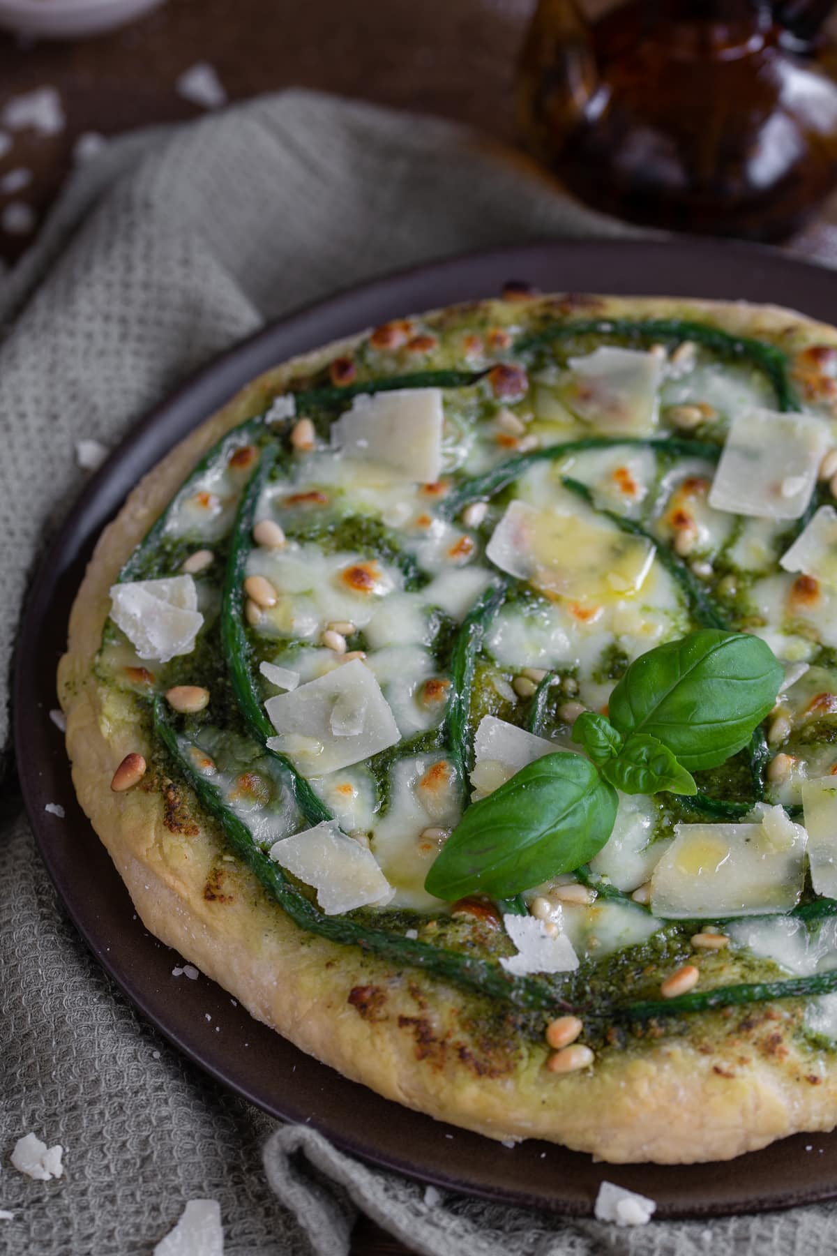 Pesto pizza with green beans topped with pine nuts and parmesan flakes.