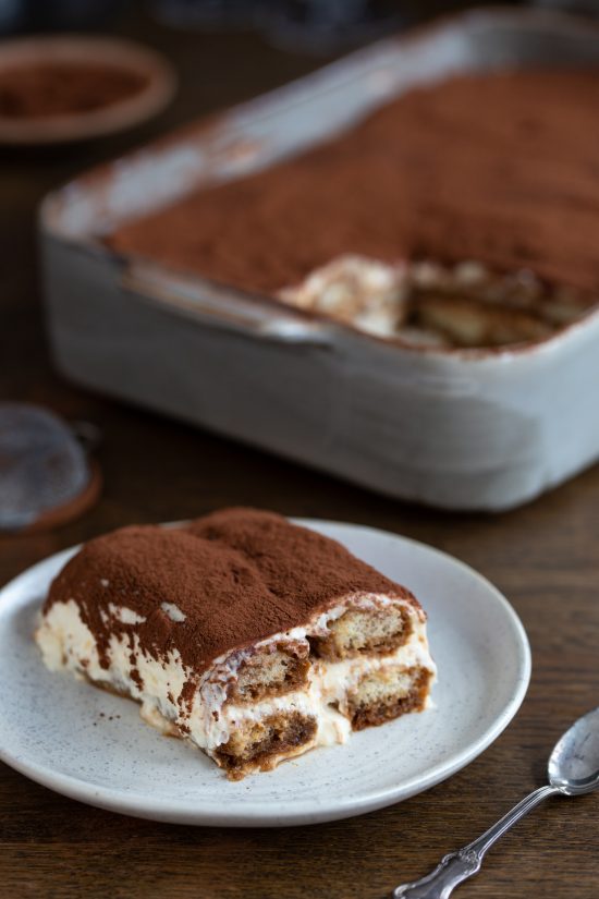 A serving of classic tiramisu on a white plate.