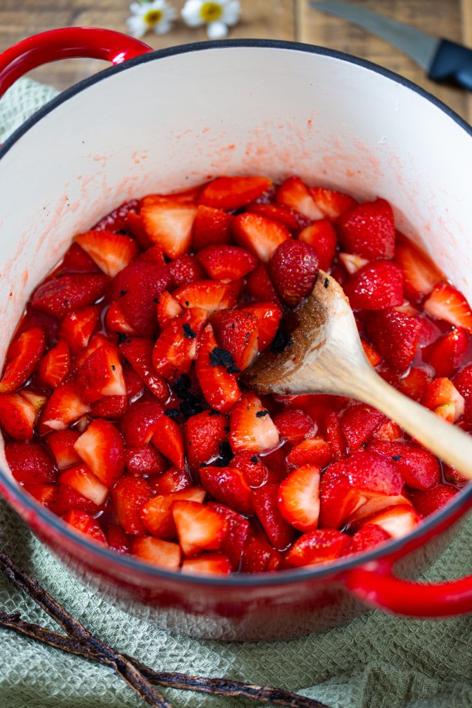 Cooking strawberries with vanilla to make jam.
