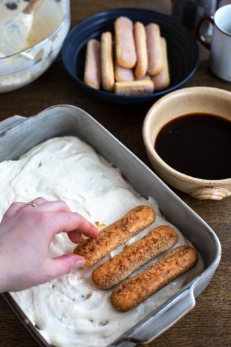 Arranging a layer of savoiardi over mascarpone cream.